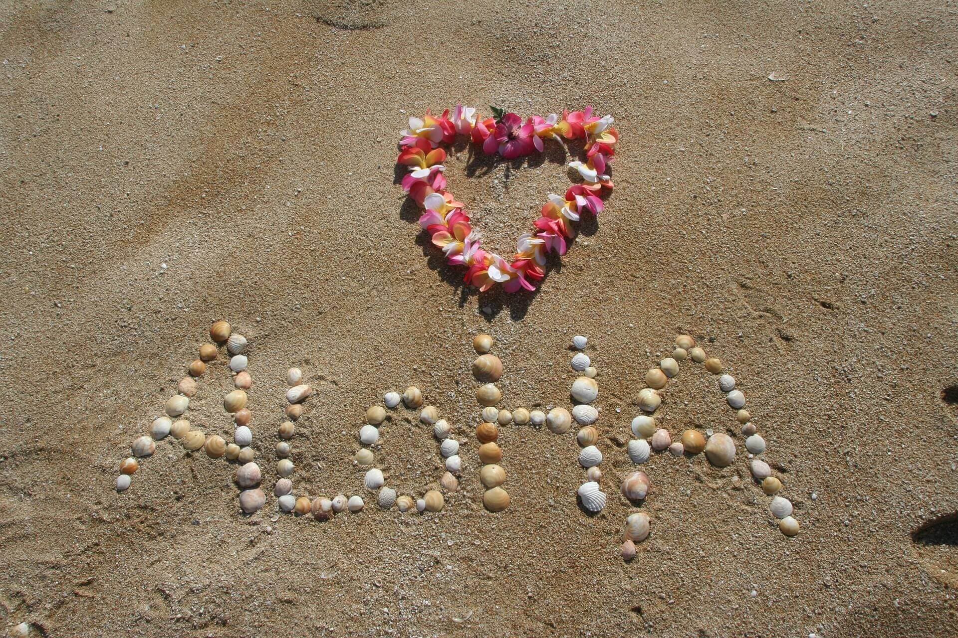 Sand with pebbles spell Aloha to welcome travelers to Hawaiʻi
