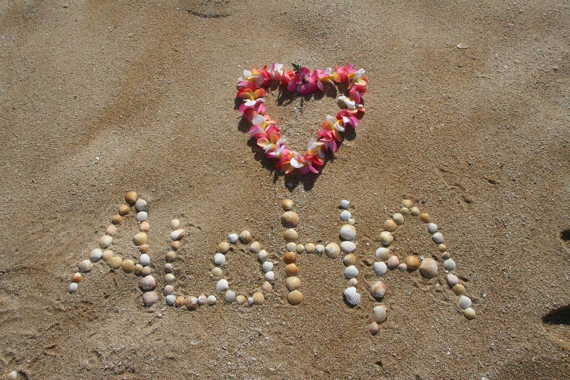 Sand with pebbles spell Aloha to welcome travelers to Hawaiʻi