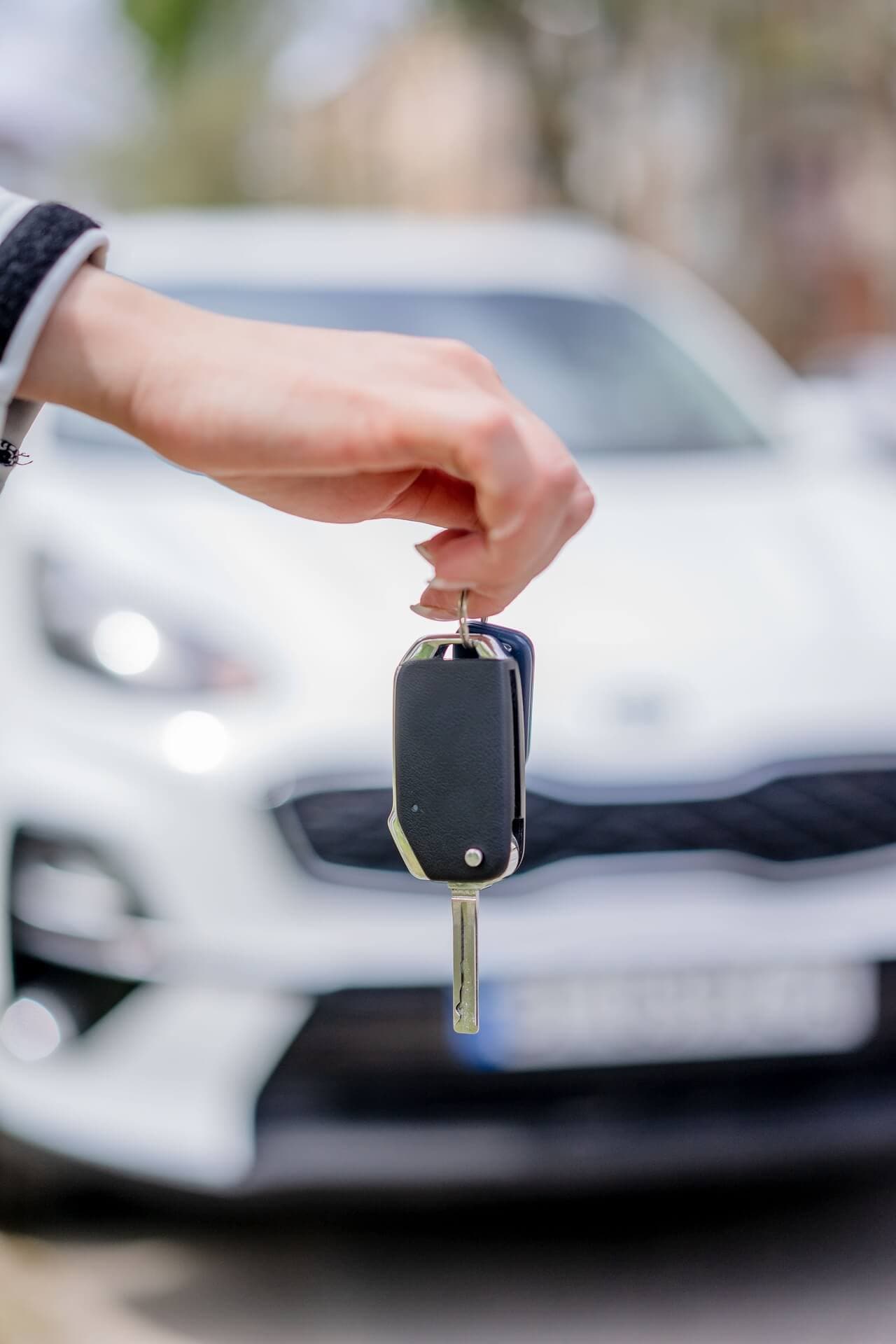 A GoVibe Member holding car keys in front of a sedan rental car