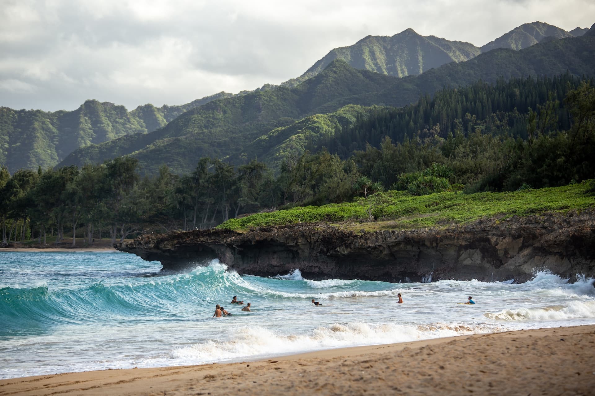 Waves on an Oahu beach with mountains in the distance