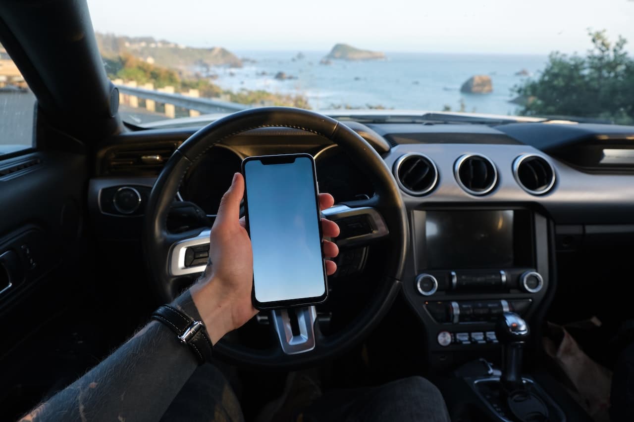 A traveler holding a phone insider an SUV